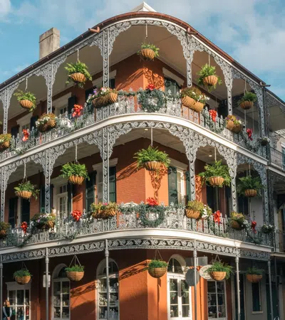 Historic building with ornate iron balconies adorned with hanging flower pots in French Quarter, New Orleans.