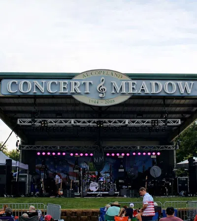 Outdoor stage setup at Al Copeland Concert & Meadow with banners for Uncle Sam Jam event and audience seating.