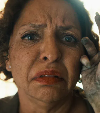 Worried woman with dirt-covered hand touching her face in a close-up emotional moment indoors.