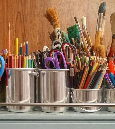 a group of pens and pencils in a glass holder