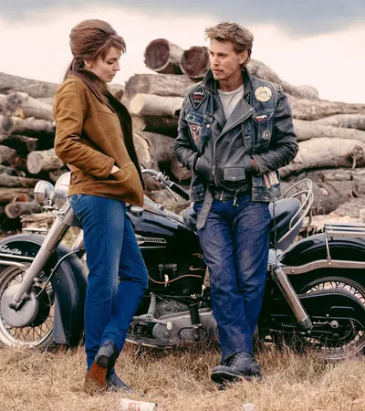 a man and woman standing next to a motorcycle
