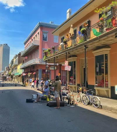 Street musicians perform on a vibrant city street lined with colorful buildings and balconies with flowers.