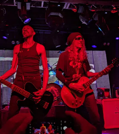 two men playing guitars on a stage