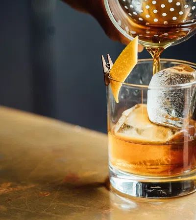 a glass of liquid being poured into a glass with a lemon slice