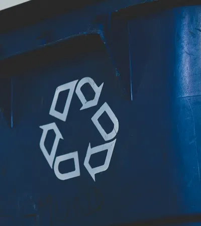 Close-up of a blue recycling bin with a white recycling symbol on it.