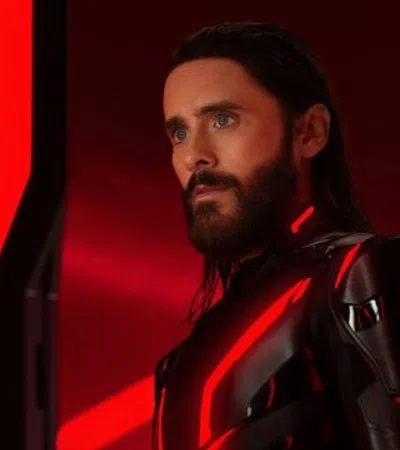 Man with beard in futuristic black suit with glowing red lights against red and black sci-fi background.