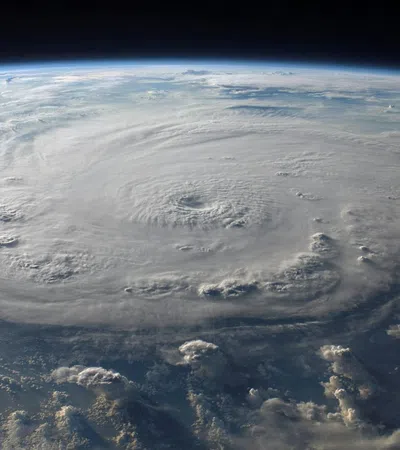 Satellite view of a massive hurricane with swirling cloud formations and a clear eye over the ocean.