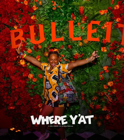 a person posing in front of a wall of flowers