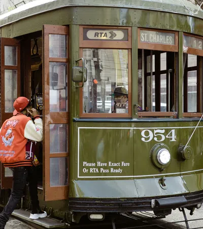 Green St. Charles streetcar number 954 in New Orleans boarding a passenger wearing a red jacket and cap