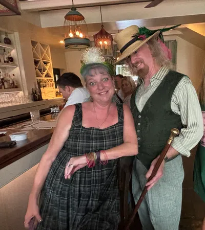 Three smiling individuals in festive attire enjoying time at a lively social gathering.
