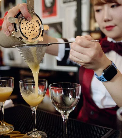 a person pouring a drink into a glass