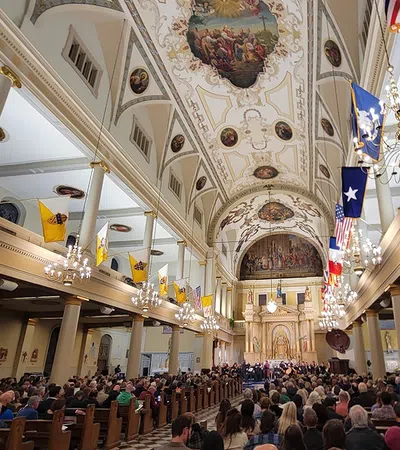 a large group of people in a church with St. Louis Cathedral in the background
