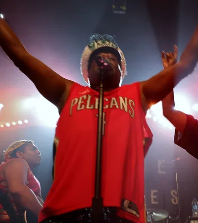a man wearing a red shirt and holding his arms up in front of a microphone
