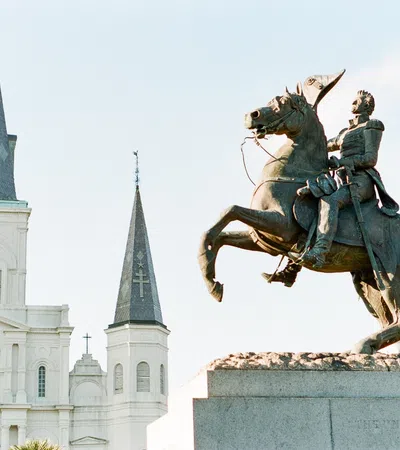 a statue of a man riding a horse in front of a white building