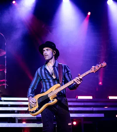 a man playing a guitar on a stage with Old National Centre in the background