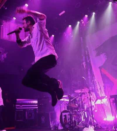 a man jumping in the air with a microphone and a drum set