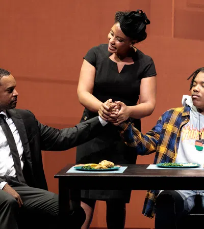 a woman standing over a man sitting at a table with a man sitting