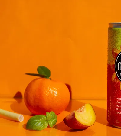a can of soda next to a fruit and a glass of orange juice