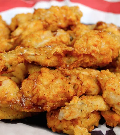 Crispy golden fried chicken wings seasoned and piled on a patriotic red, white, and blue surface.