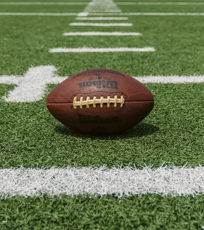 Brown Wilson football placed on green turf with white yard lines in a stadium field.
