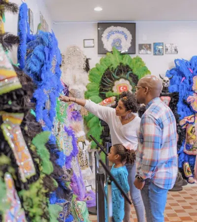 Family explores colorful, feathered Mardi Gras Indian costumes in an indoor cultural exhibit.