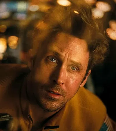 Man with intense expression looking upward in a dimly lit room with blurred lights in the background