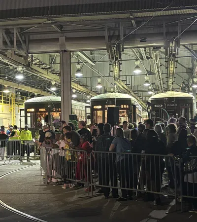 Crowd of people inside a large train depot with vintage streetcars and industrial lighting overhead