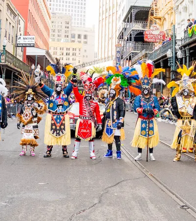 Colorful Mardi Gras Zulu tribe members in ornate costumes and feathered headdresses standing in a New Orleans street parade.