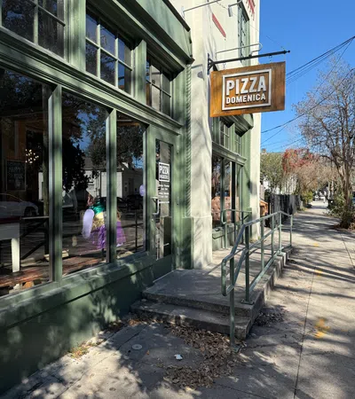 Charming exterior of Pizza Domenica with inviting windows and a welcoming sign on a sunny day.
