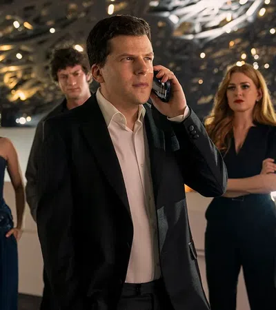 Group of six serious young adults in stylish outfits with one man in the center on a phone call under modern lighting.