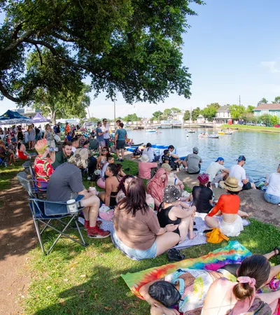a group of people sitting on the grass by a body of water