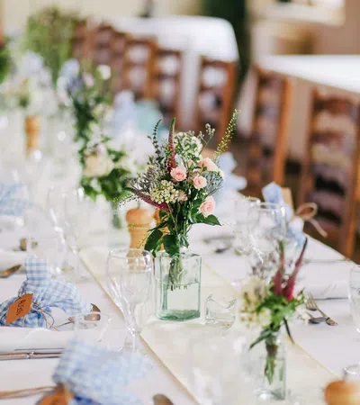 Elegant wedding reception table adorned with flowers, glasses, and blue checkered accents.