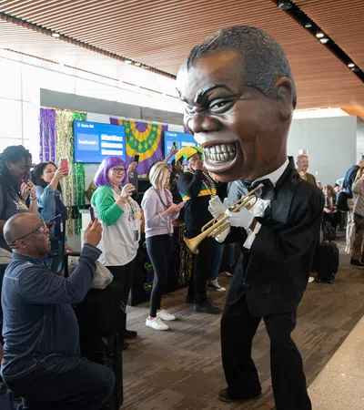 Crowd at indoor event watches performer in big mask playing trumpet and another performer in lobster costume.