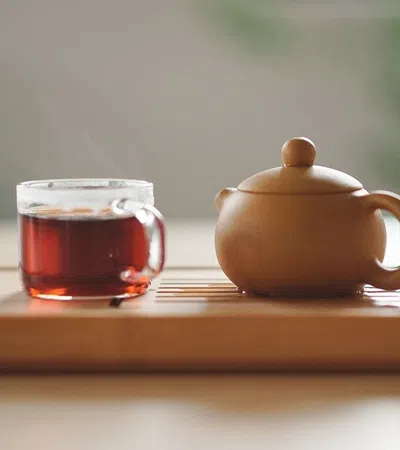 a teapot and a glass of tea on a tray