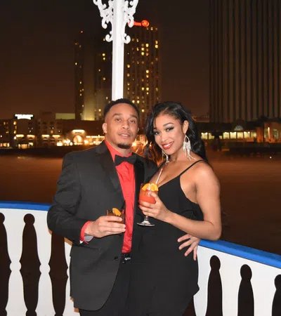 a man and woman posing for a picture with a body of water in the background