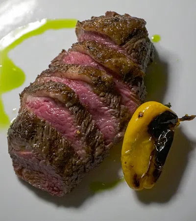 a piece of meat with a green and yellow substance on a white plate