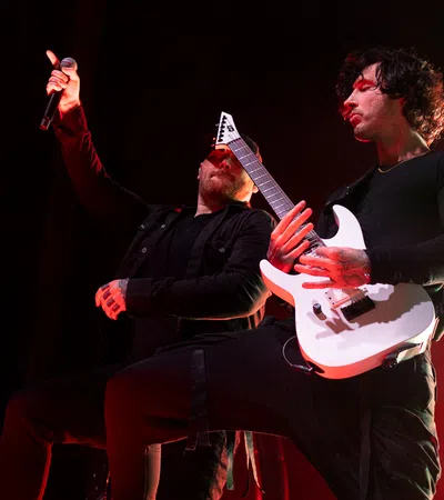 a man playing a guitar next to a man playing a guitar