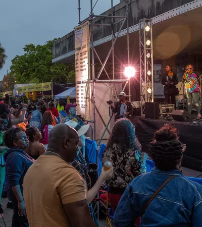 Crowd enjoying live music at a vibrant outdoor festival with performers on stage.