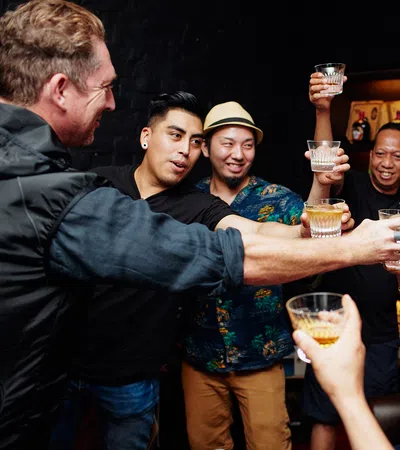 Group of friends raising glasses together in a cheerful toast at a cozy indoor gathering.