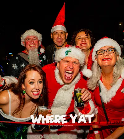 a group of people wearing santa hats and holding cans of beer