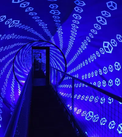 Tunnel walkway with glowing blue hexagonal patterns creating a futuristic visual effect.