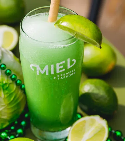 a glass of green liquid with limes and limes