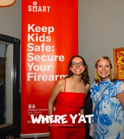 a couple of women posing for a picture in front of a sign