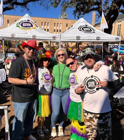 Group of five people wearing colorful tutus and Sober Safe Spot shirts at an outdoor event under tents