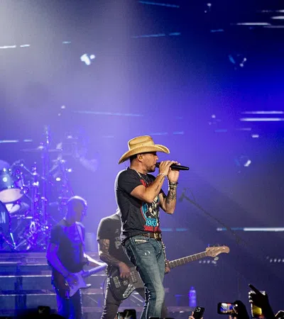 a man singing into a microphone on stage with a band playing