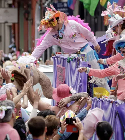 People in colorful costumes on parade float reaching out to enthusiastic crowd during festive street celebration