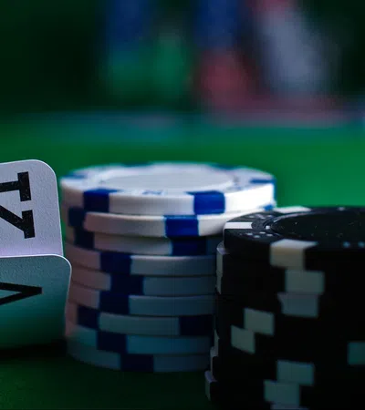 Close-up of poker table with a King and Ace of clubs and stacks of blue, black, and green poker chips.