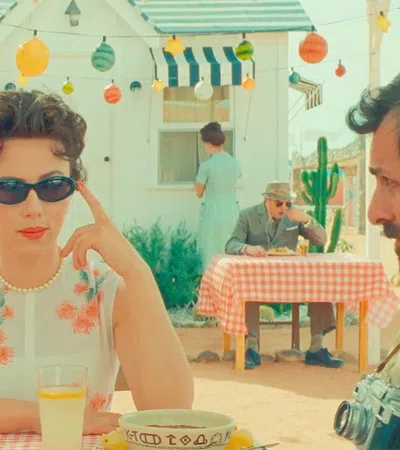 a man and woman sitting at a table with food and drinks