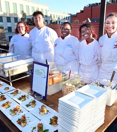 a group of people in white coats standing next to a table with food