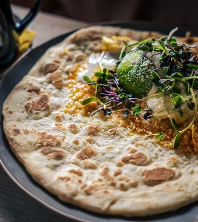 a pizza with broccoli and cheese on a plate